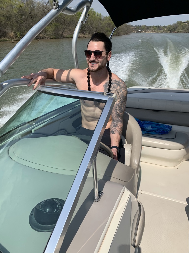 Matt smiling while driving a boat on a river